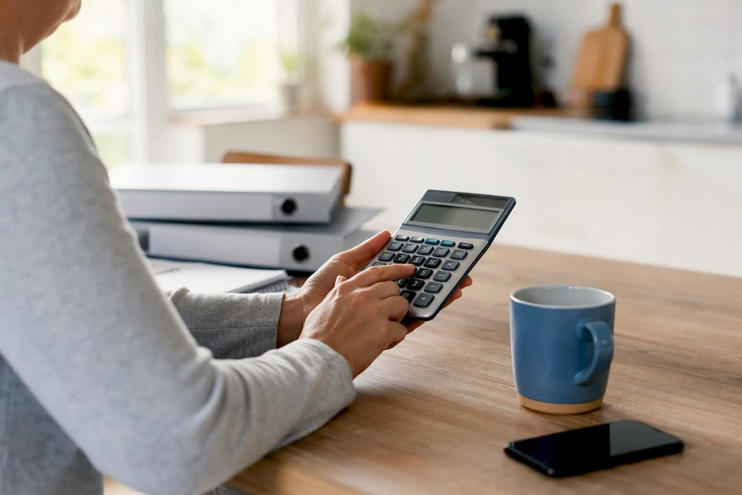 1787898866028 Hands Using Calculator On Wood Desk
